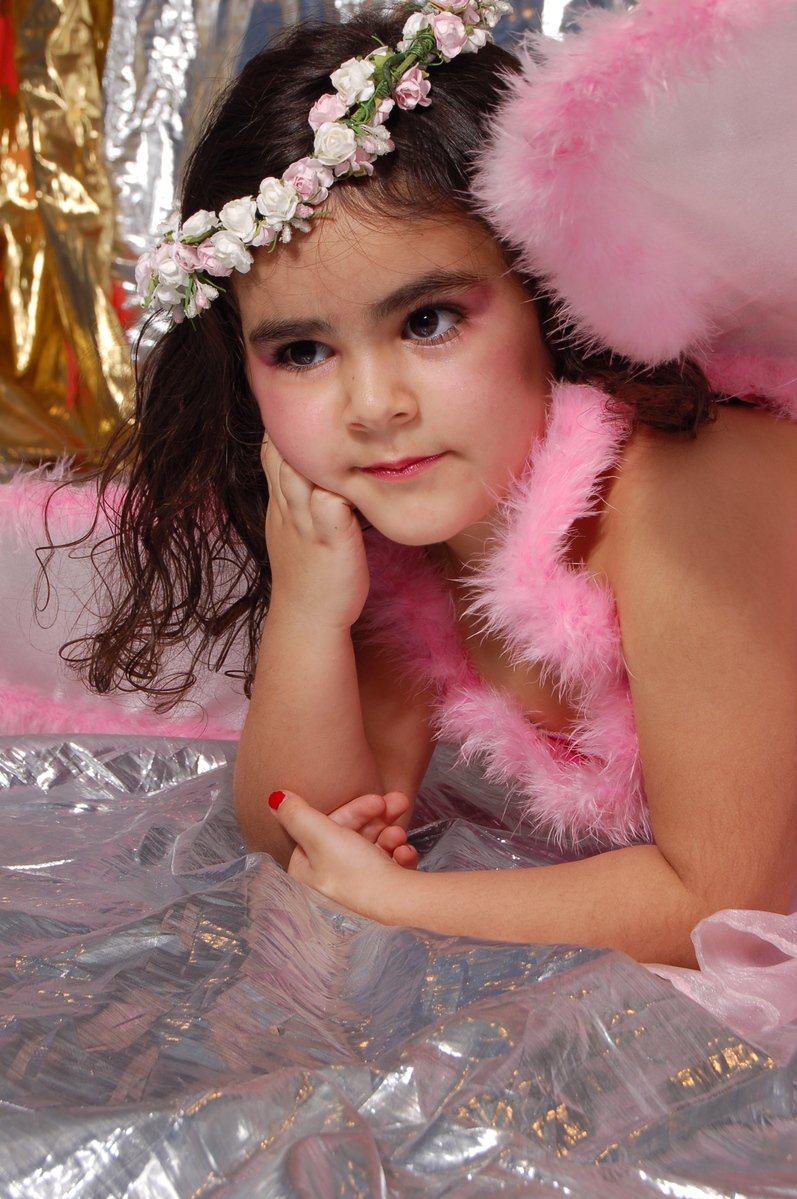 the girl wearing the pink feather angel outfit is posed