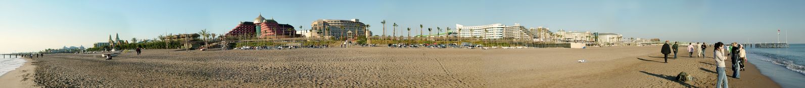 a bunch of people walk along the beach