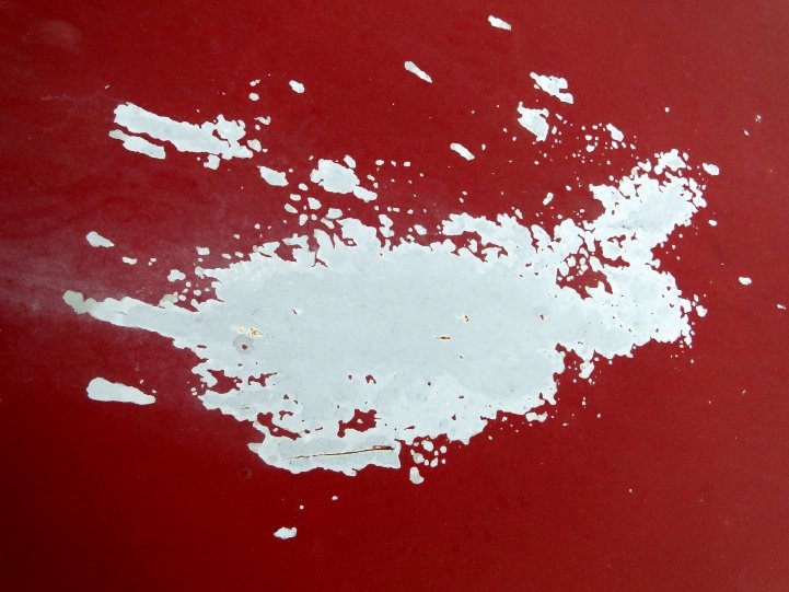 a red parking meter with white paint chipping it