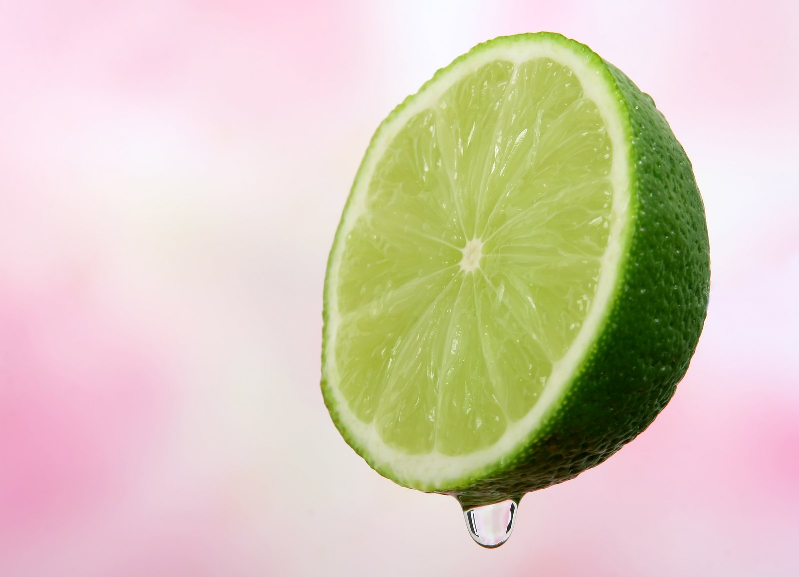 a lime in the air with water dripping on it