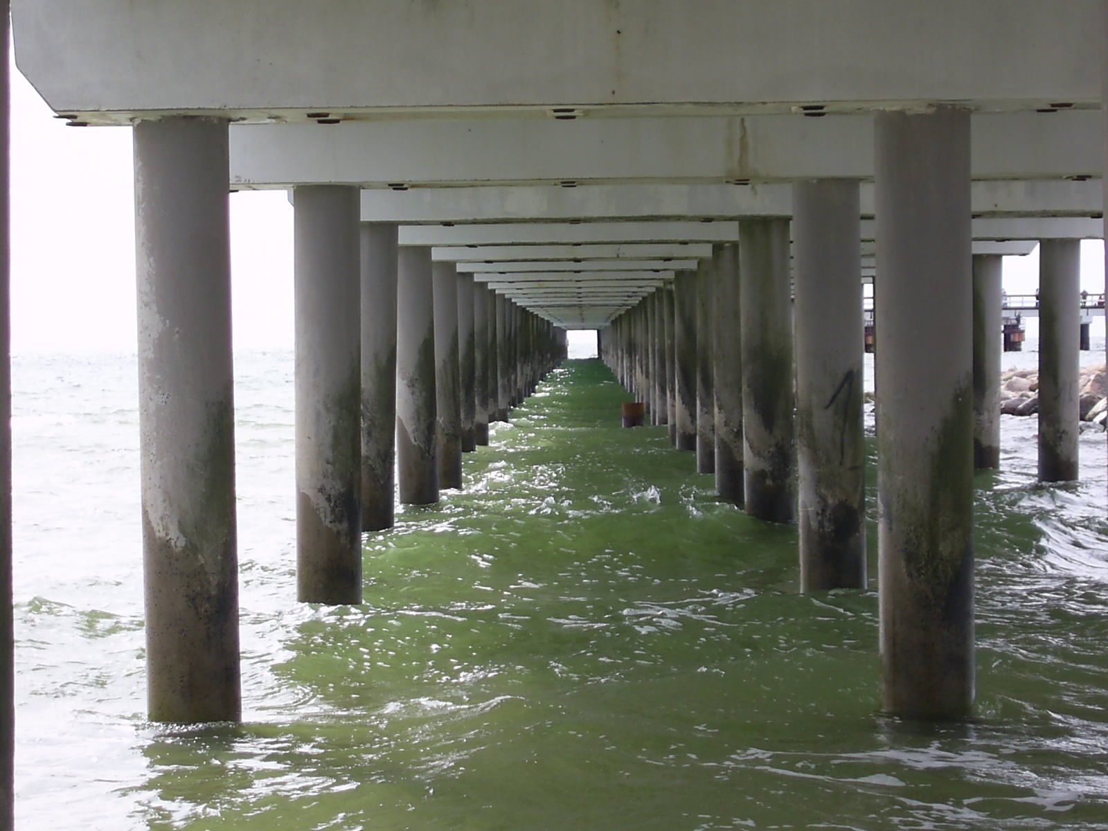 a long dock in the water under a pier