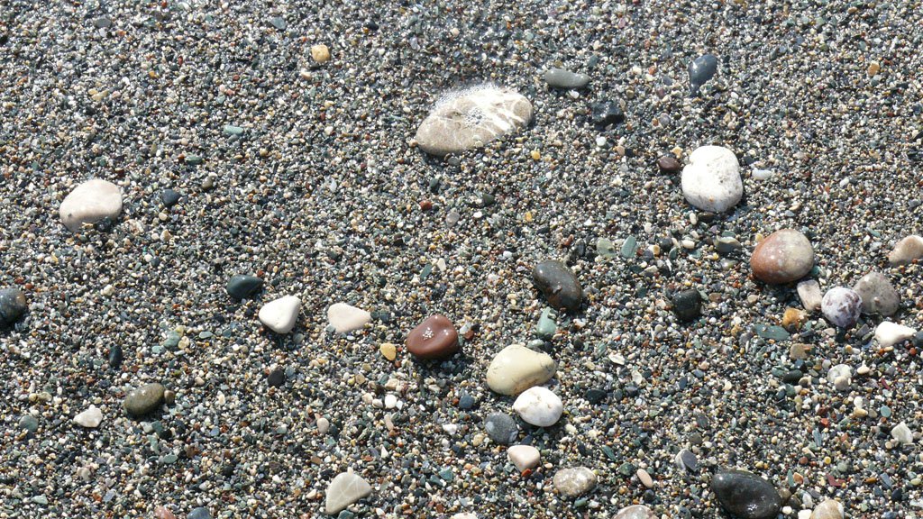 several rocks on a sandy beach covered in sand