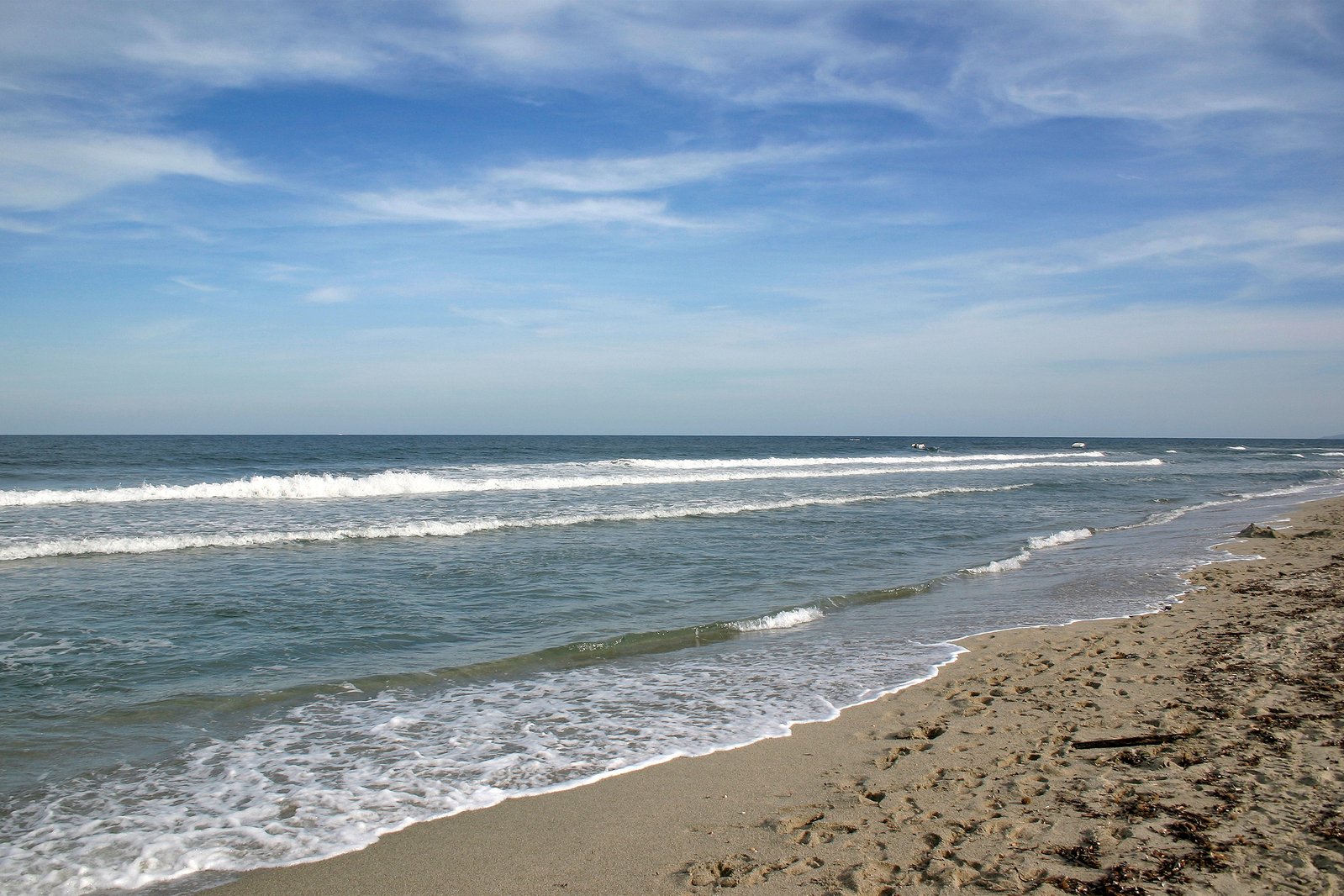 the shore line is rocky and the beach has waves crashing