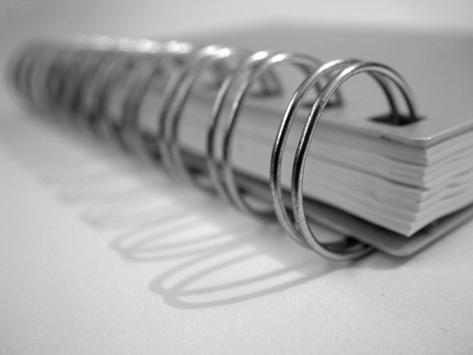 an open spiral metal book on white paper
