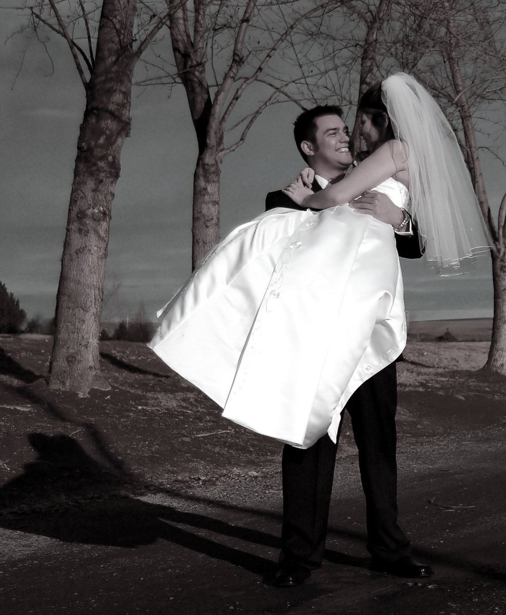 a man carries a bride along the street as they pose