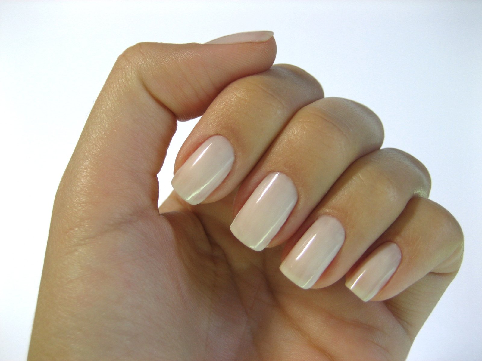 hand holding a manicured nail that is white and has a white background