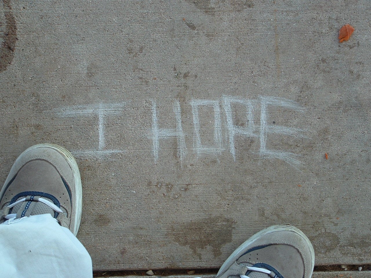 someone with sneakers standing on the sidewalk writing on it