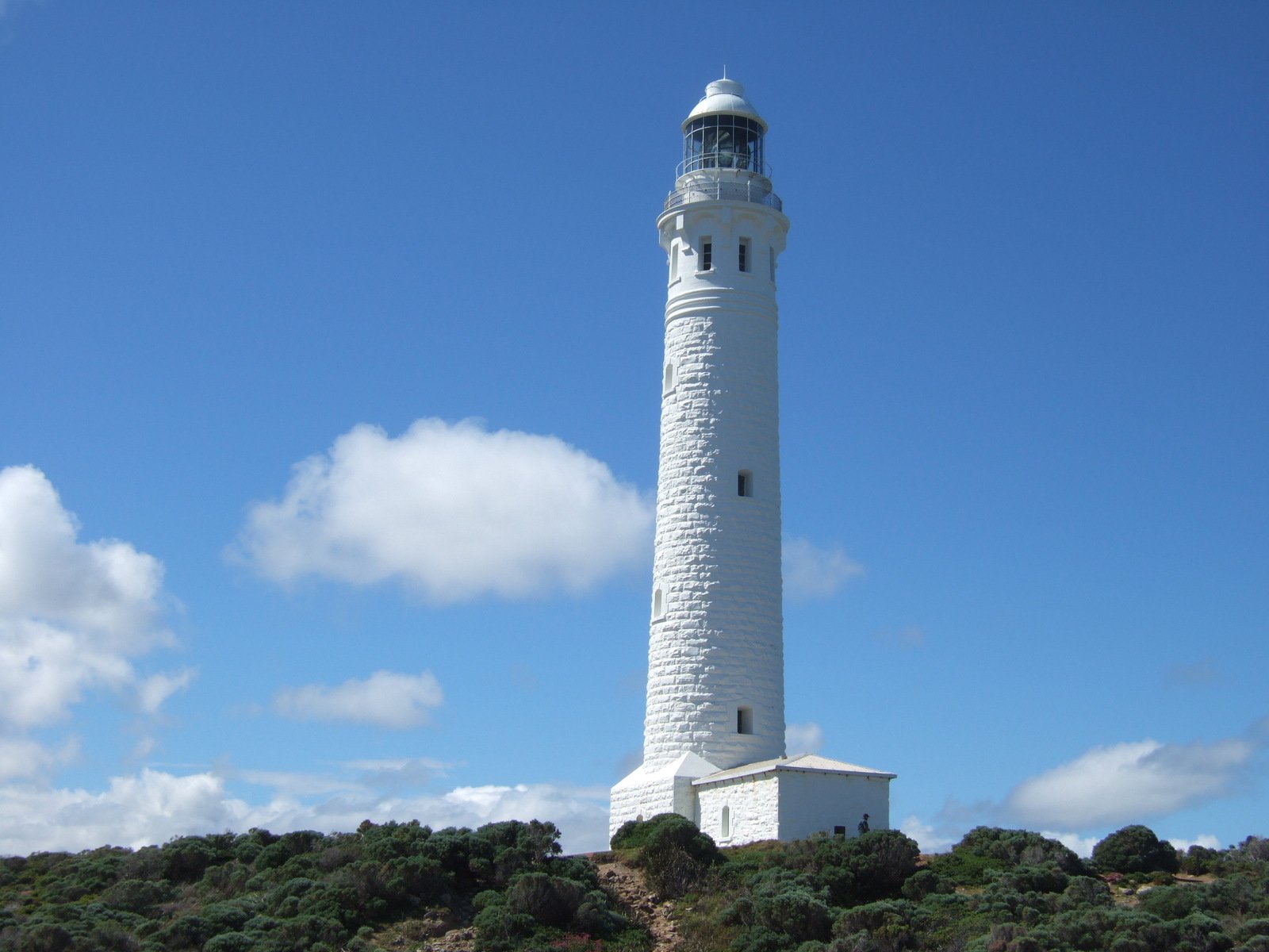 the lighthouse is surrounded by a small hill