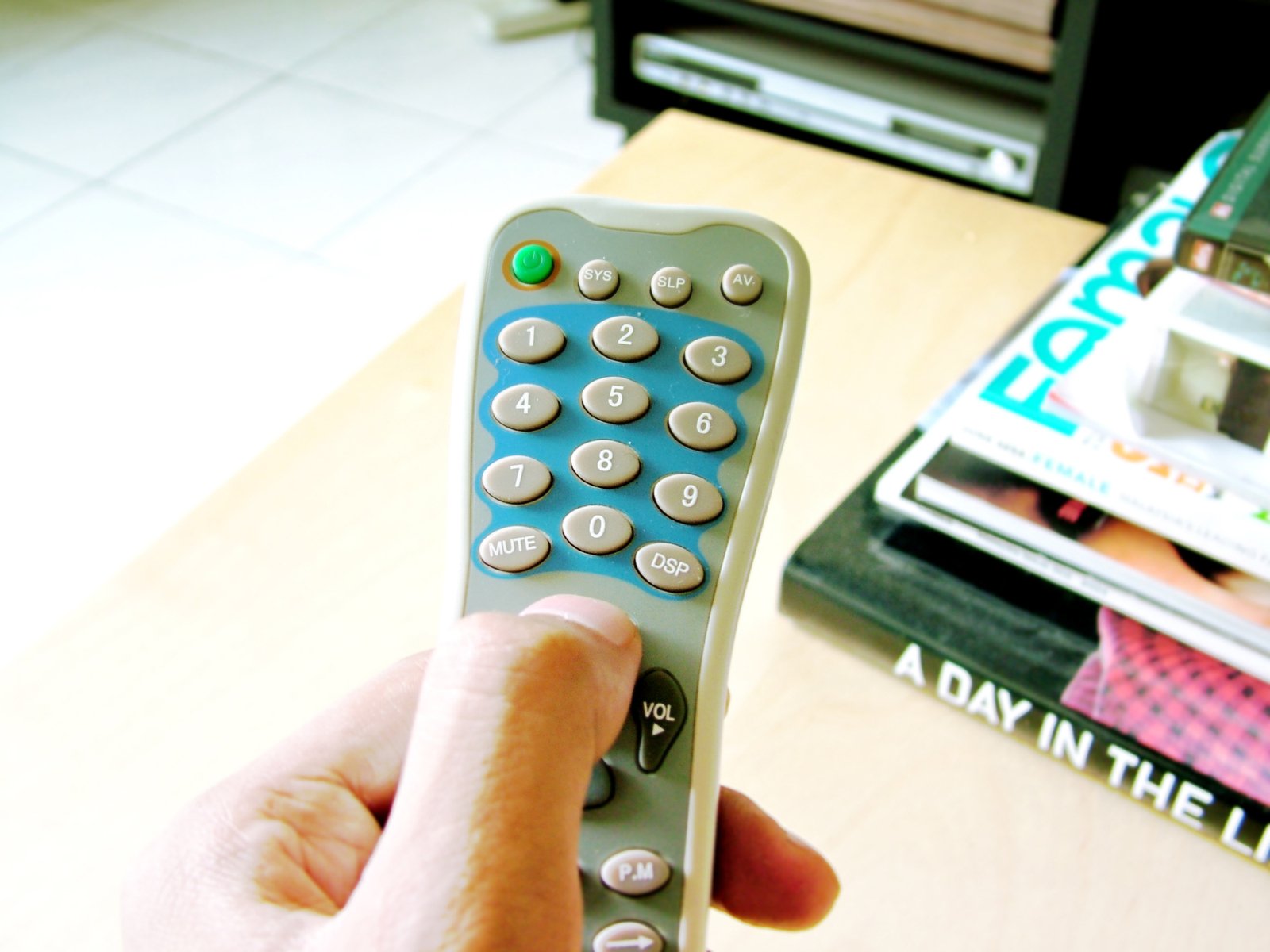 a remote control in hand on the table