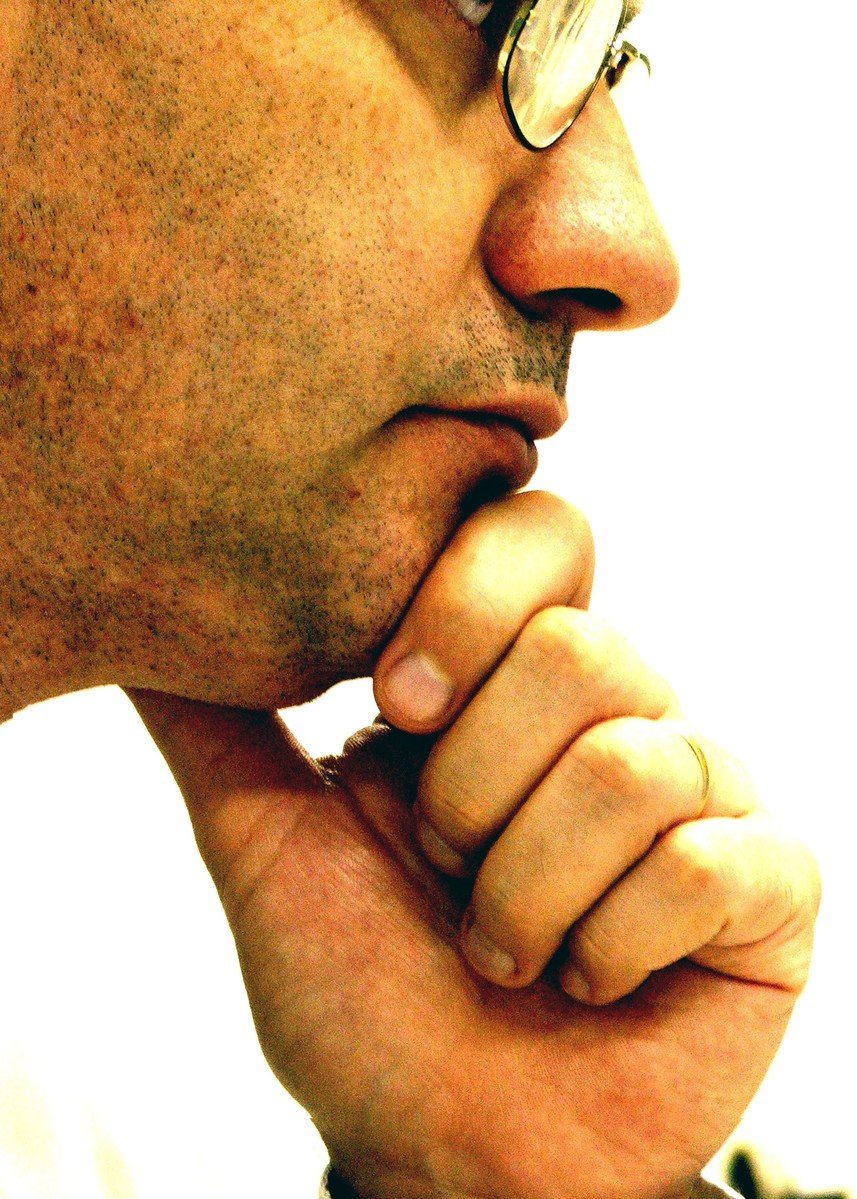 a closeup of a man wearing glasses and praying