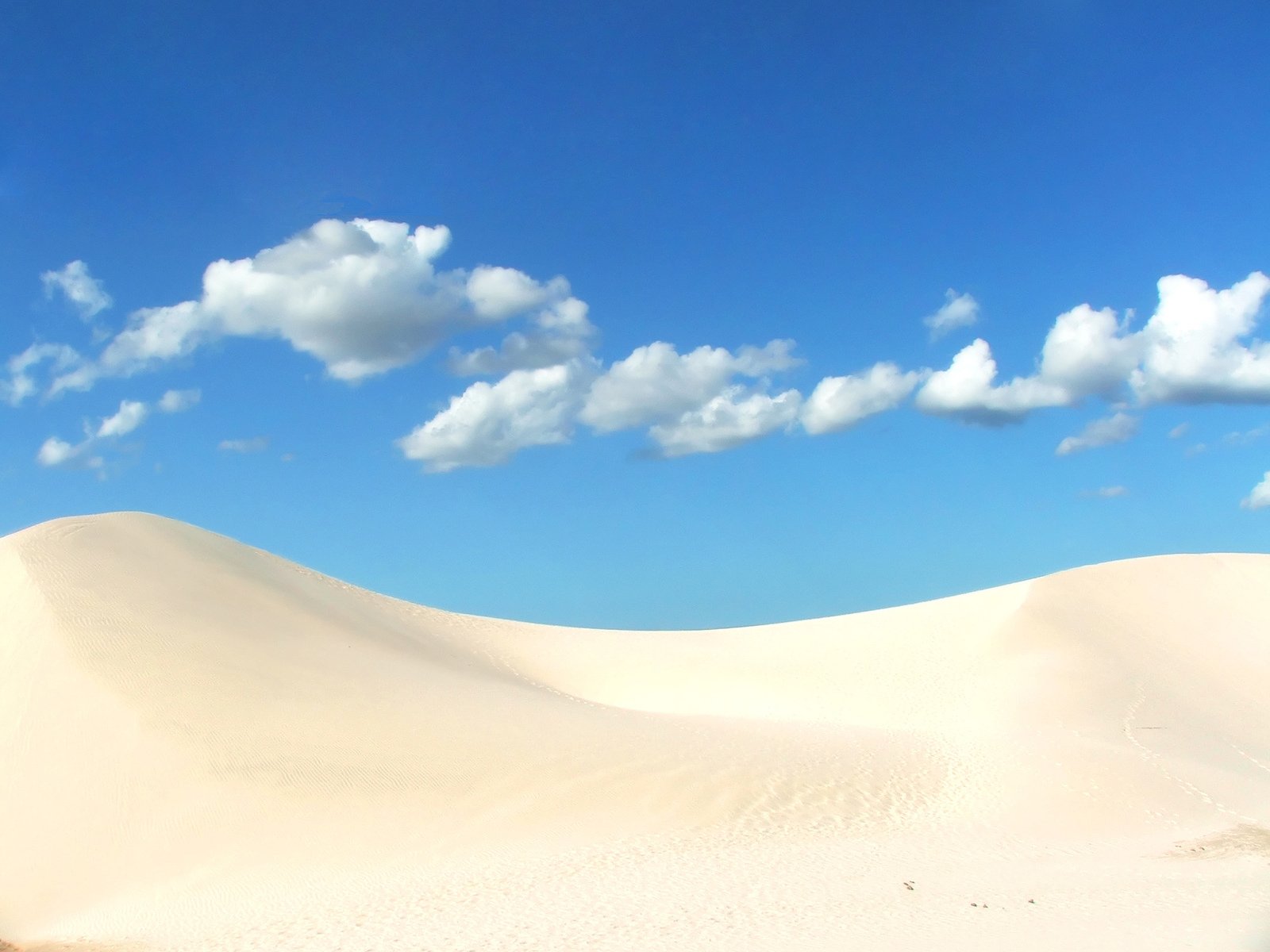 some very pretty clouds over a big white sand dune