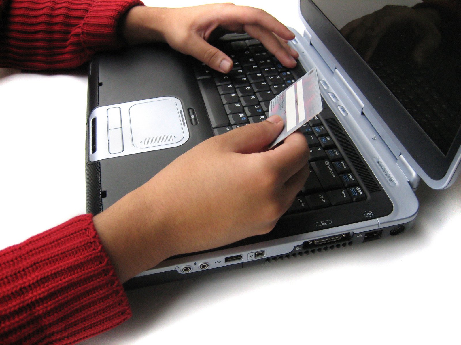 someone holding a small white business card while using a laptop