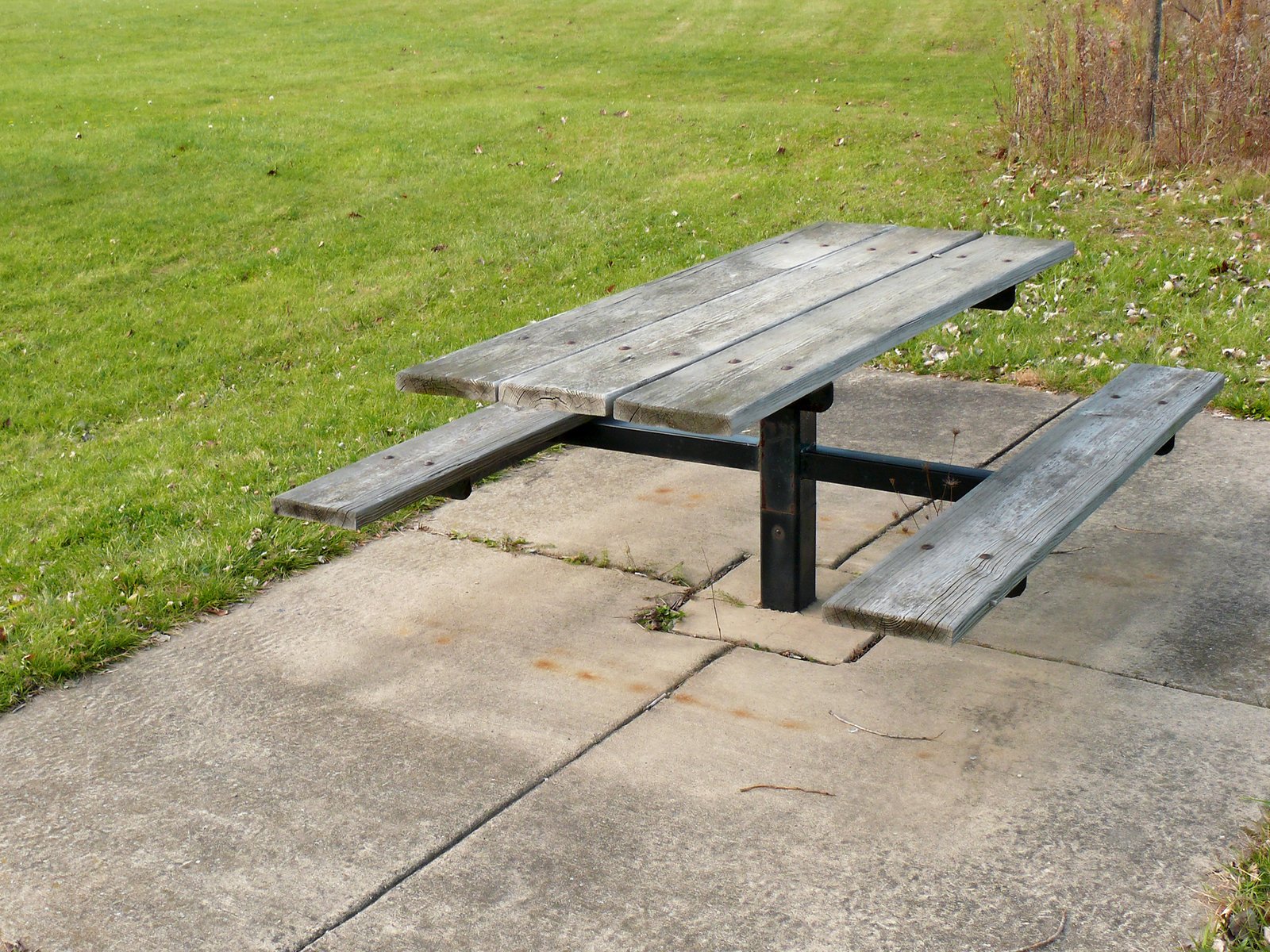 a small picnic table sitting on concrete in the grass