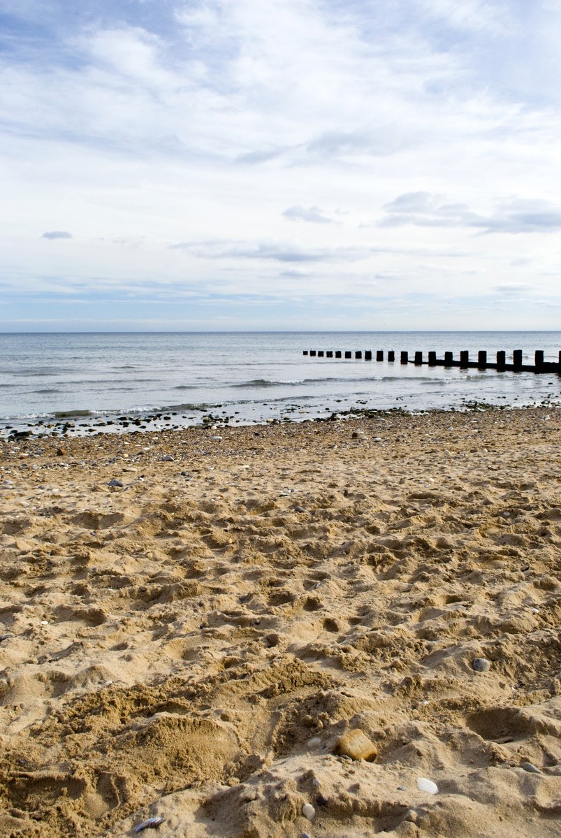 a bench in the sand facing an ocean