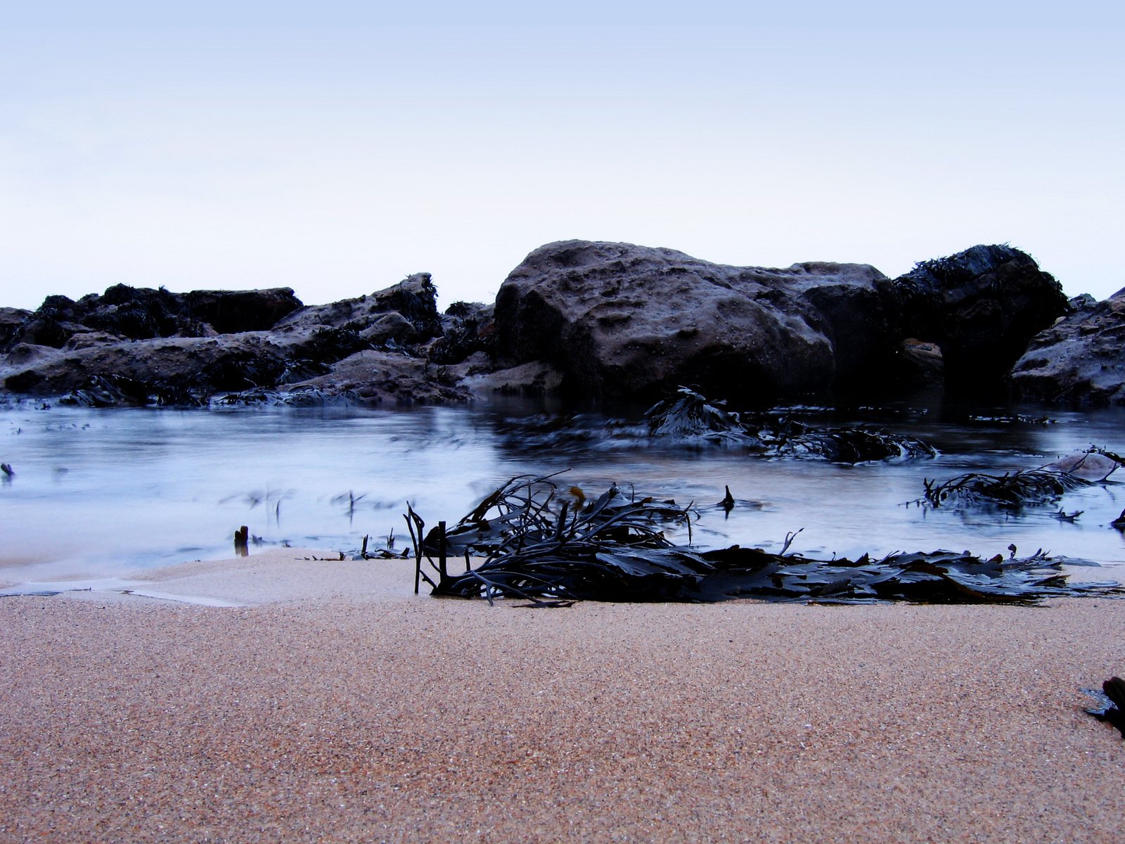 a view of a sand beach with rocks on it