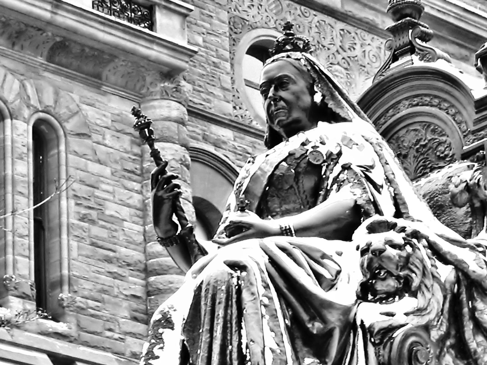 a statue of a lady sitting on a lion with the city's clock behind her