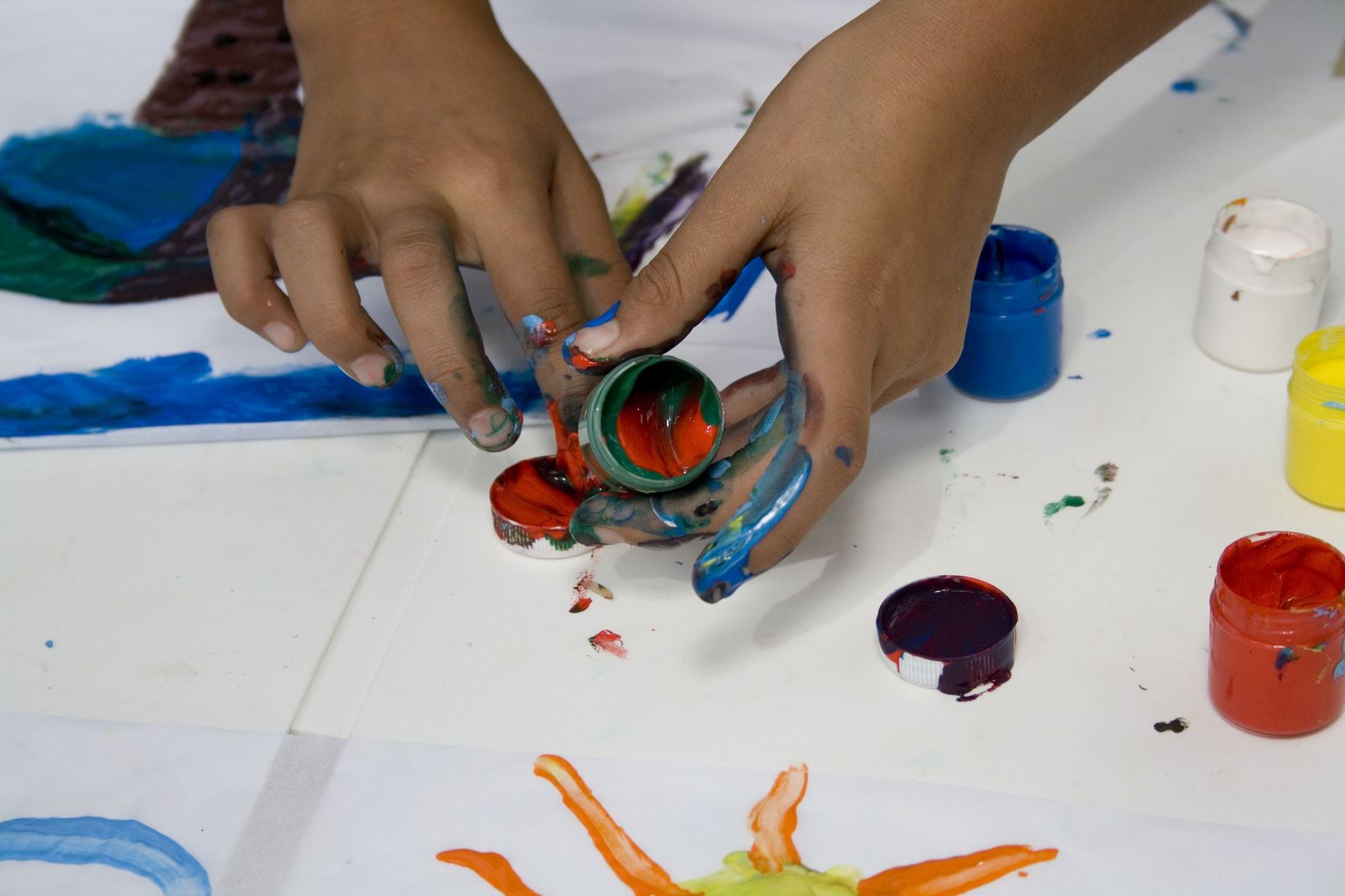 the hands are holding onto a paint can that is sitting on a white table