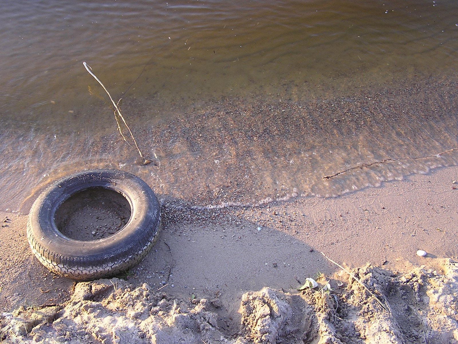 there is a tire on the sand near the water