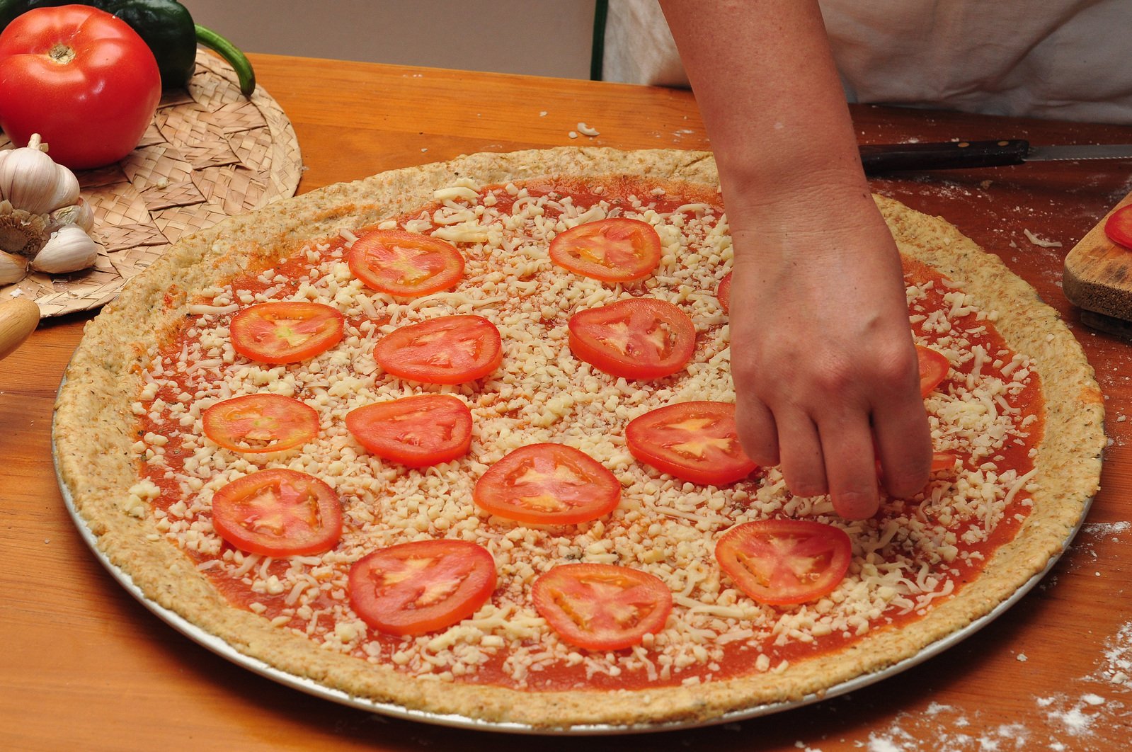 someone making a pizza topped with lots of tomatoes