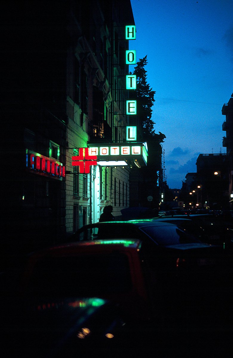 a nighttime view of cars parked in front of the neon sign