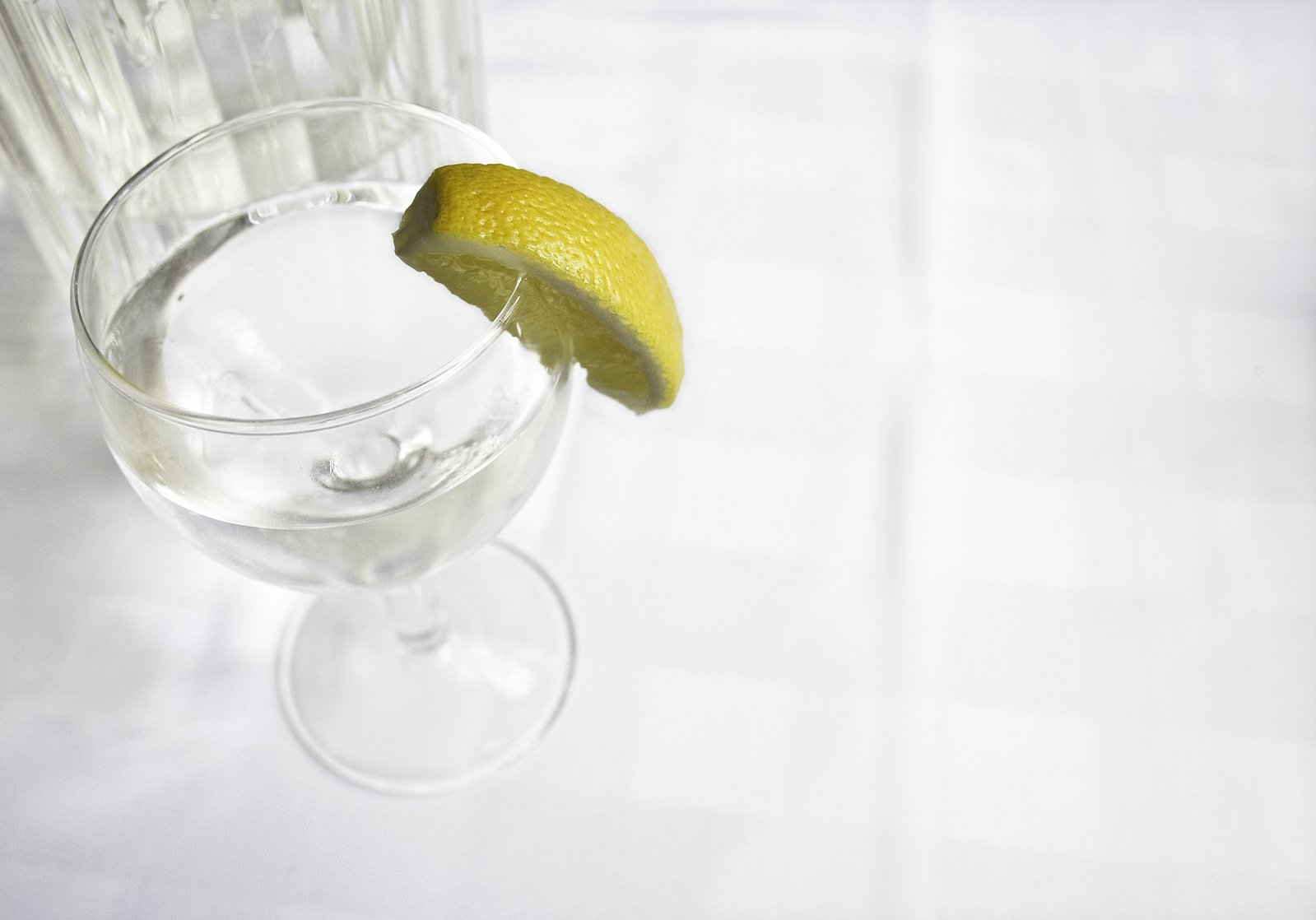a half finished margarita glass with one lemon peel