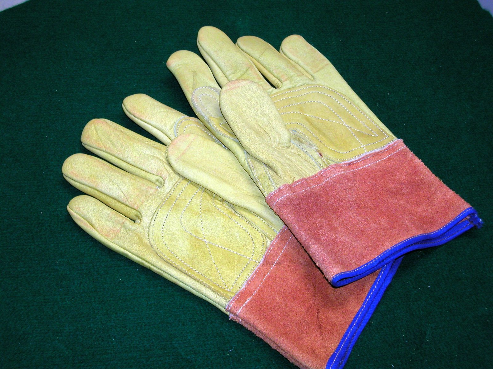 a pair of yellow and orange leather gloves laying on top of a green table