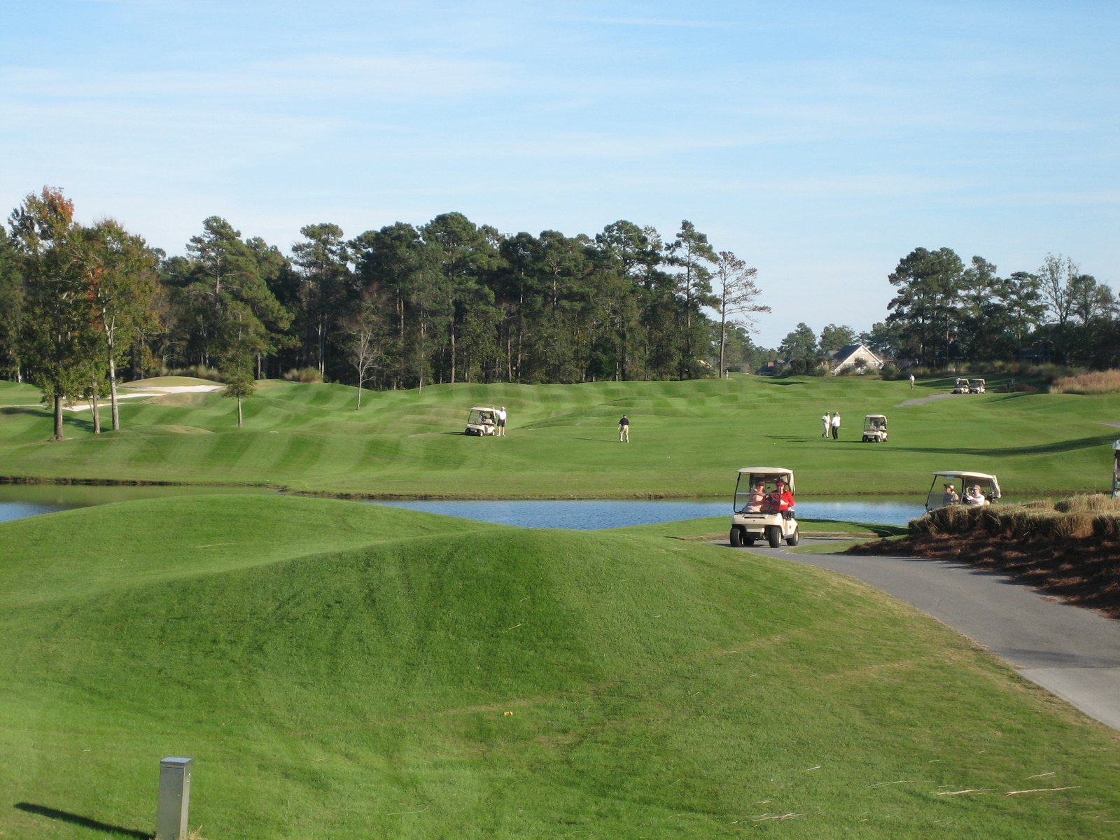 a golf course with a body of water and several parked cars