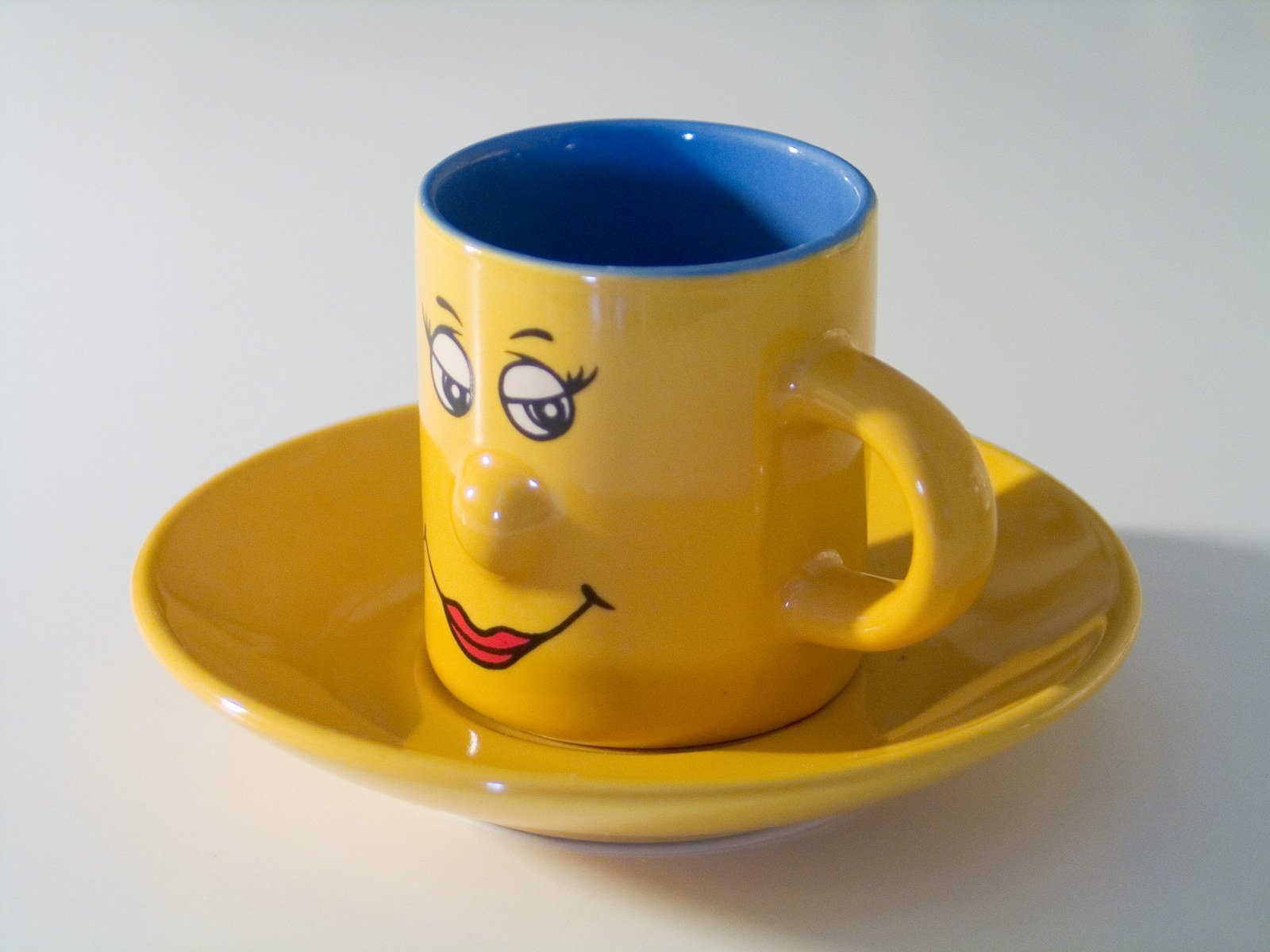 a yellow cup on a saucer with a face