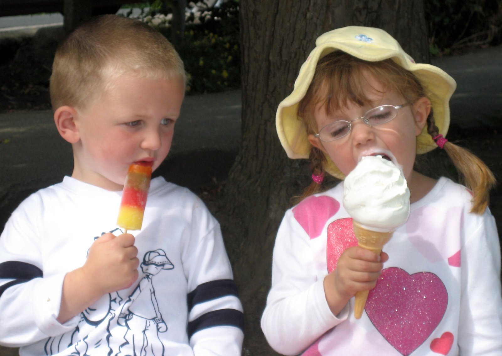 two little s sitting by each other eating ice cream