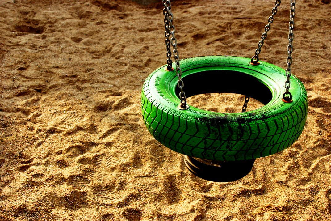 an empty tire swing sits in the sand