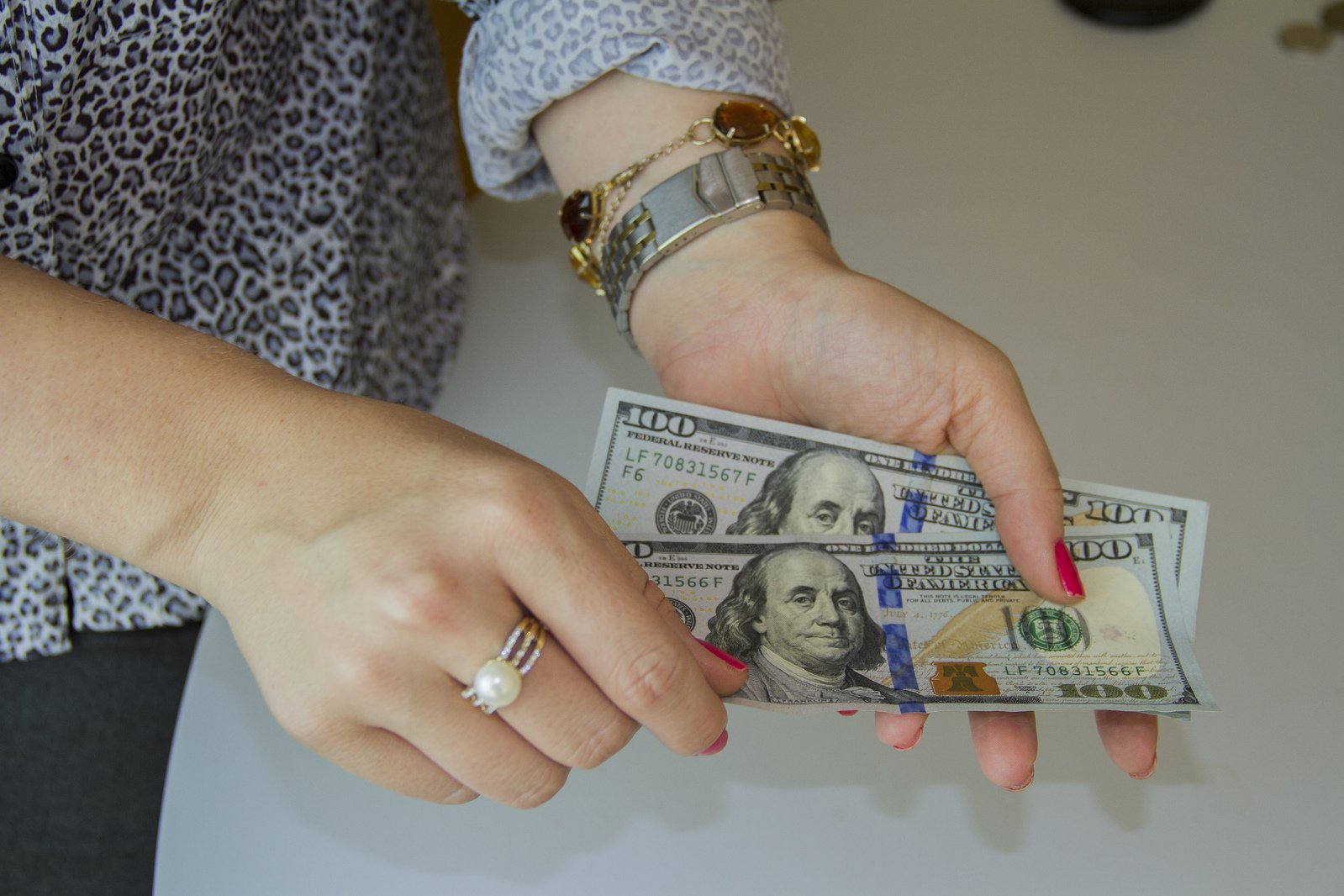 a woman's hands holding a stack of one dollar bills