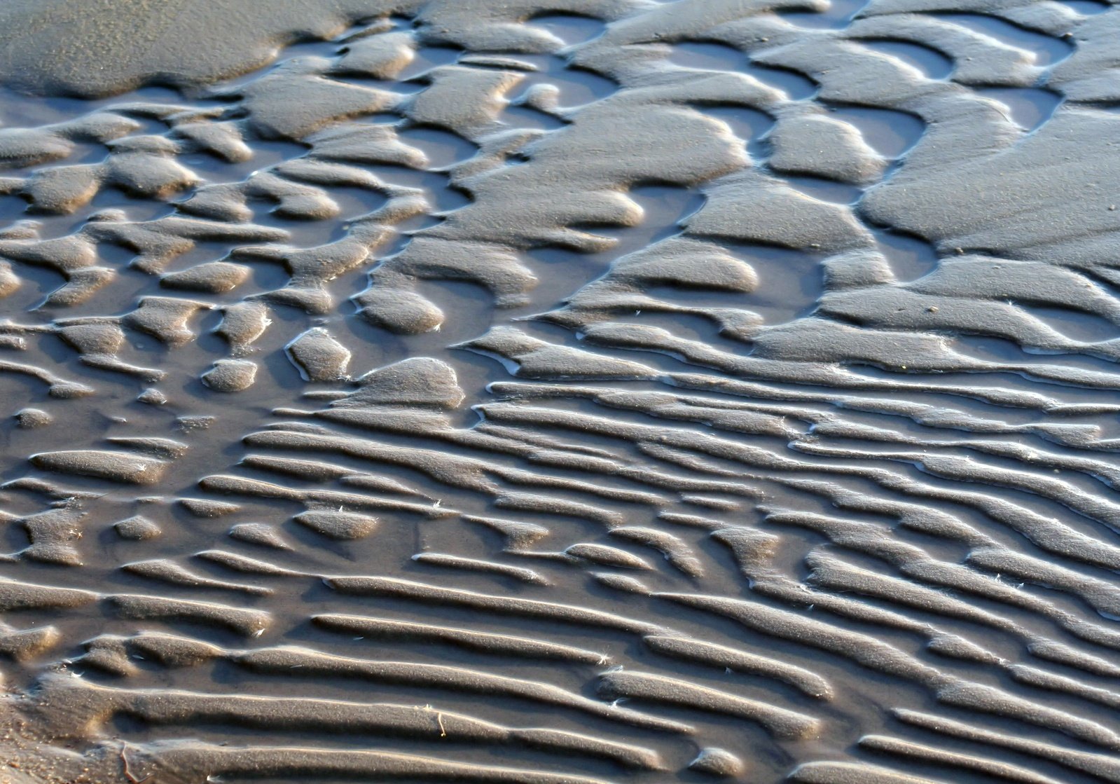 patterns of wet sand being reflected by water