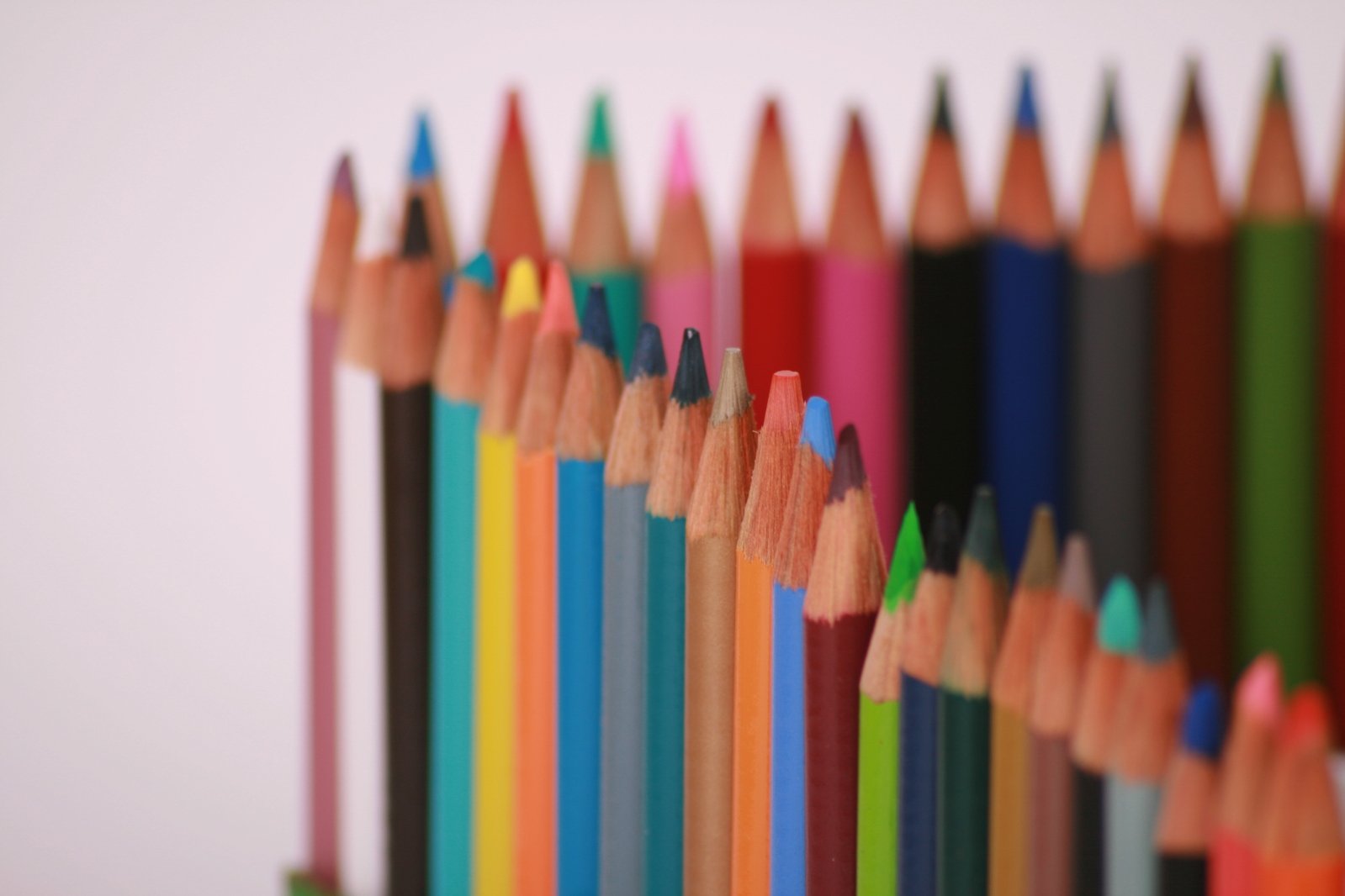 a row of different colored pencils lined up on a white background