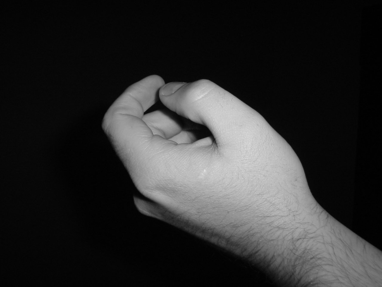 a hand holding soing in the dark and its left hand is pointed upward