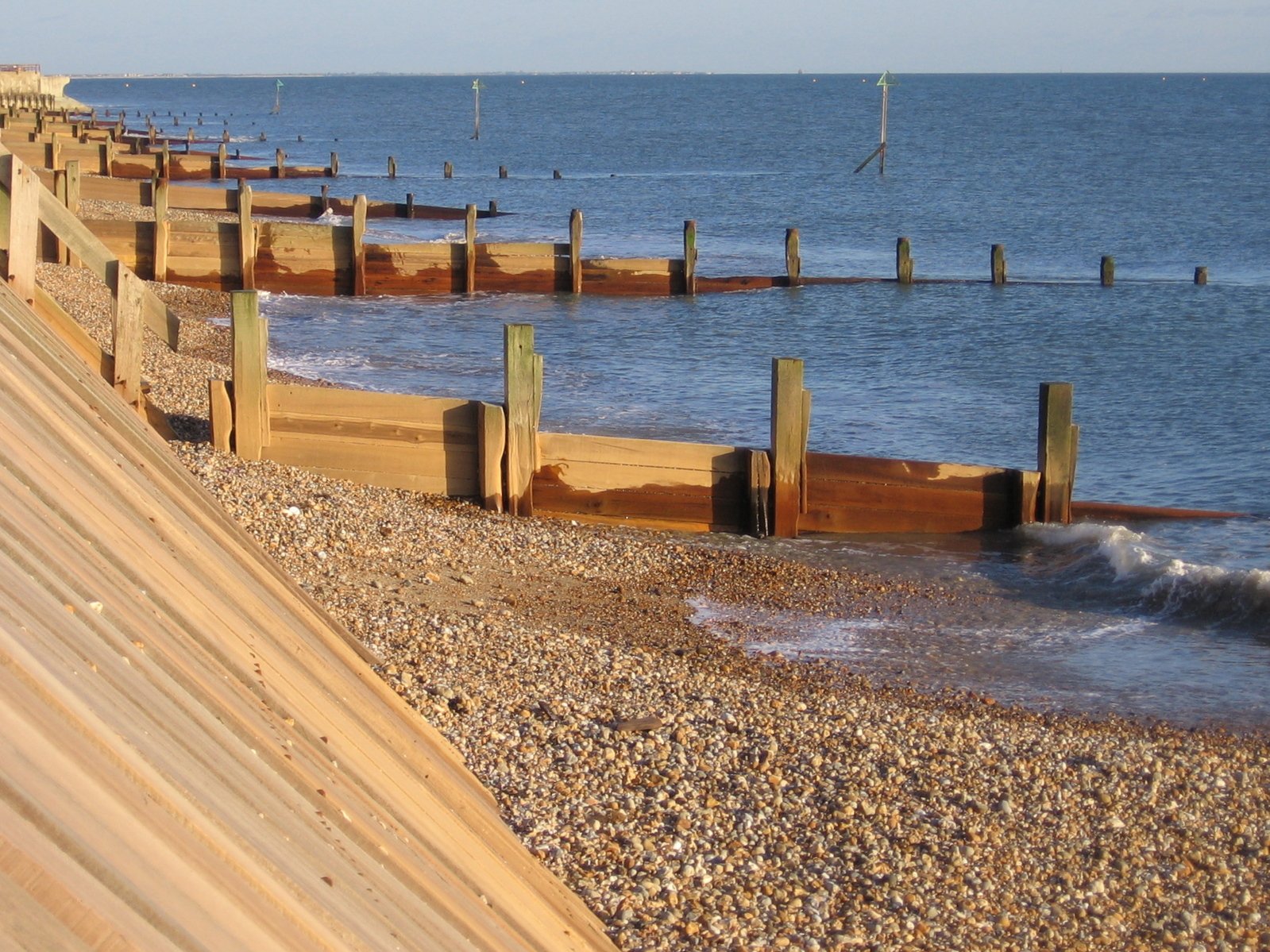 a long pier lined with wooden posts near the water