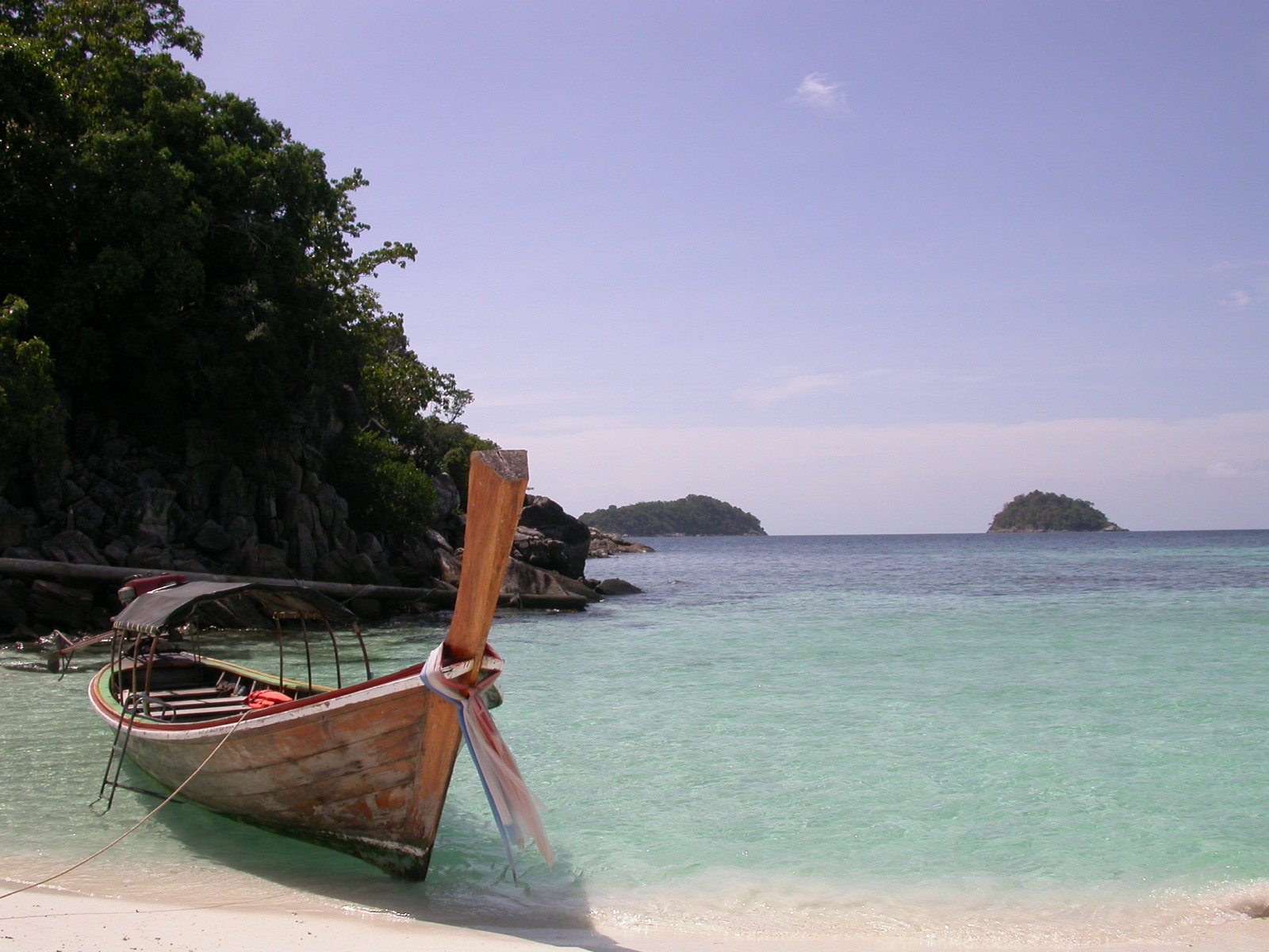 an old boat sitting on top of a sandy beach