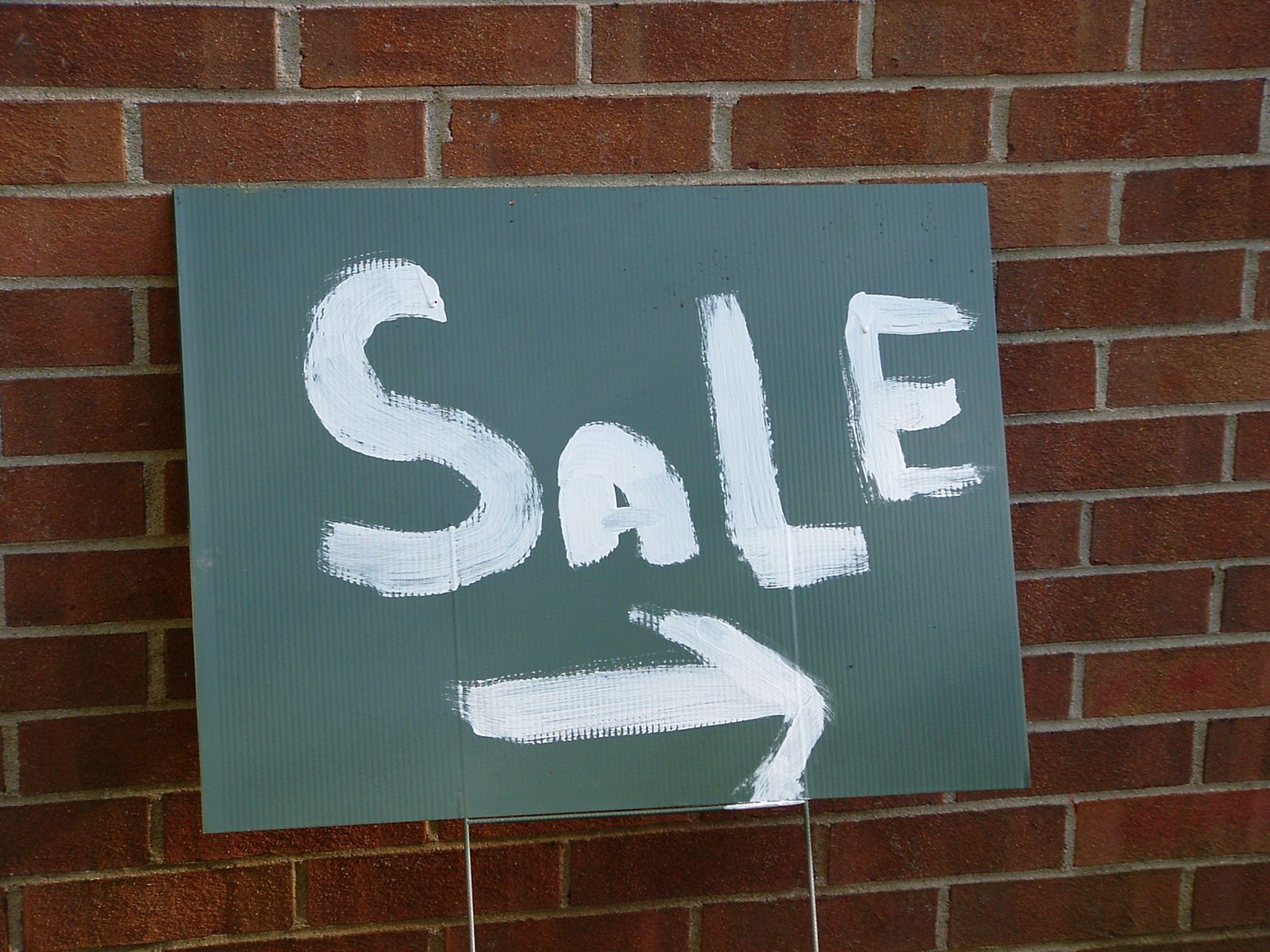 a green sign hanging from the side of a brick building