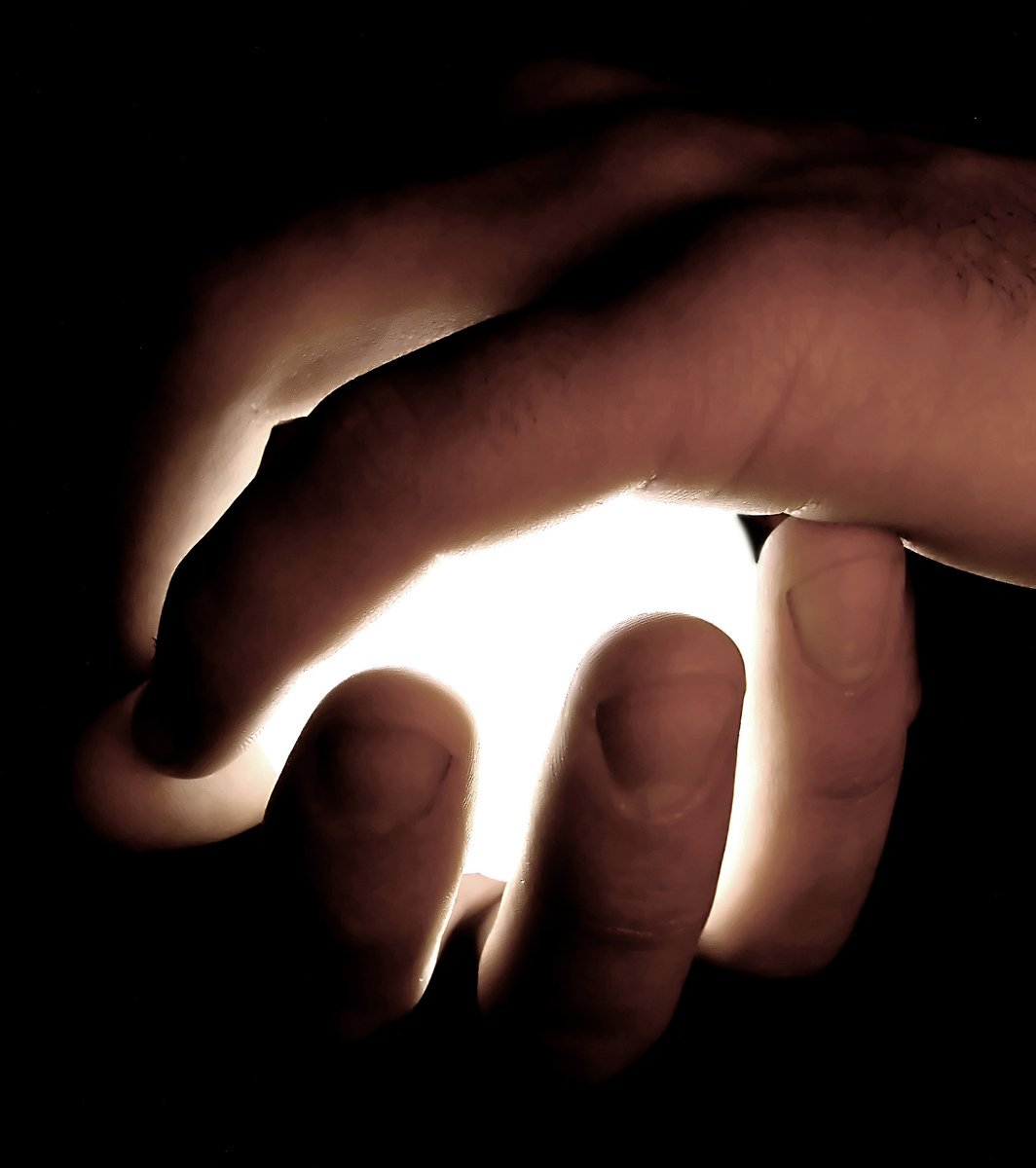 two hands on a dark surface light up the palm