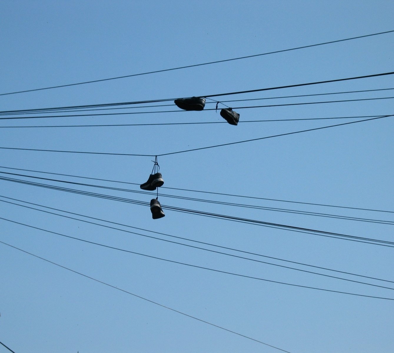 four pairs of shoes hanging on to some wires