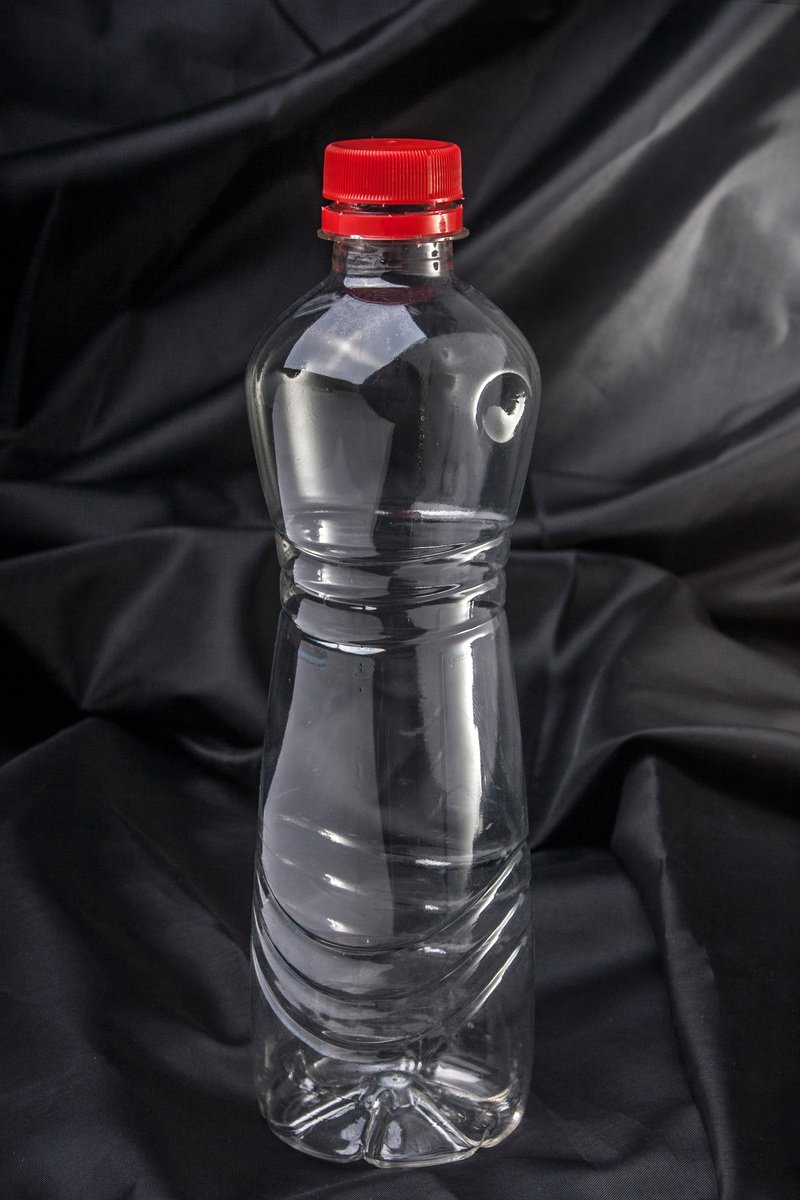 a clear glass bottle with a red lid