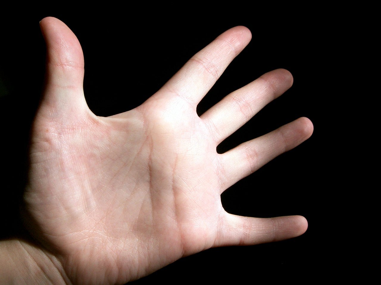 someones hand extending toward the camera on a black background