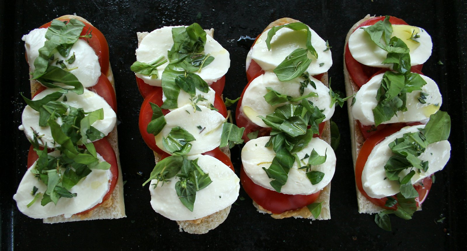 a couple of open sandwiches on a black surface