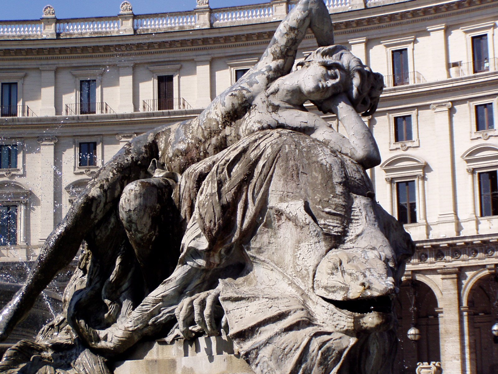 an outdoor sculpture with a circular building in the background