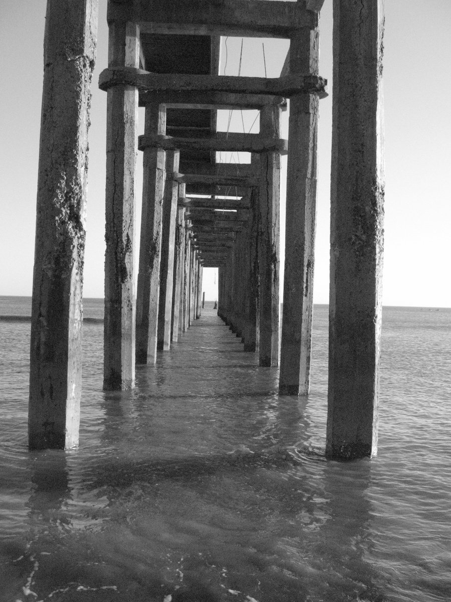 the ocean is shown beneath a long pier