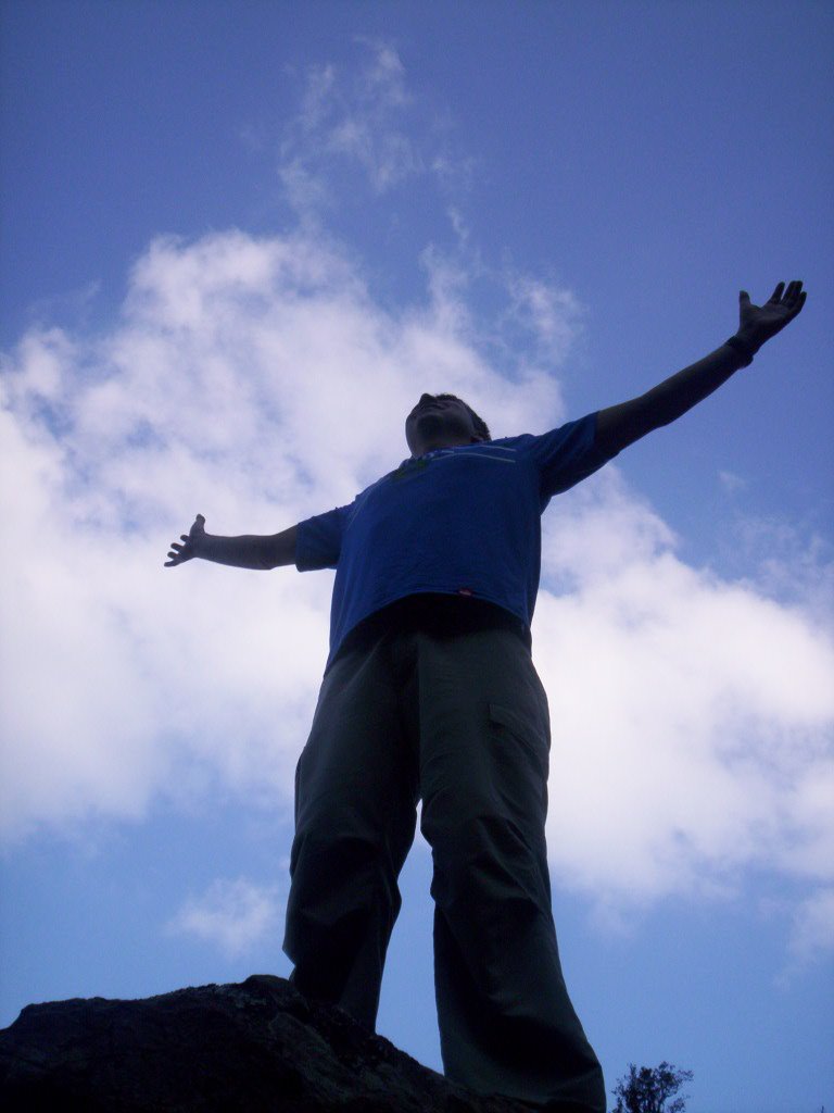 a man standing on top of a hill in the middle of the day