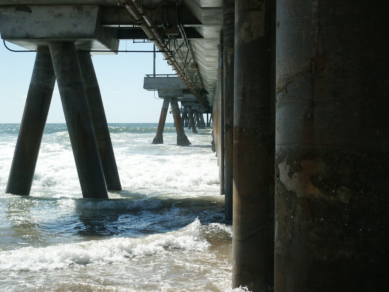 the ocean beneath a fishing dock with waves crashing in