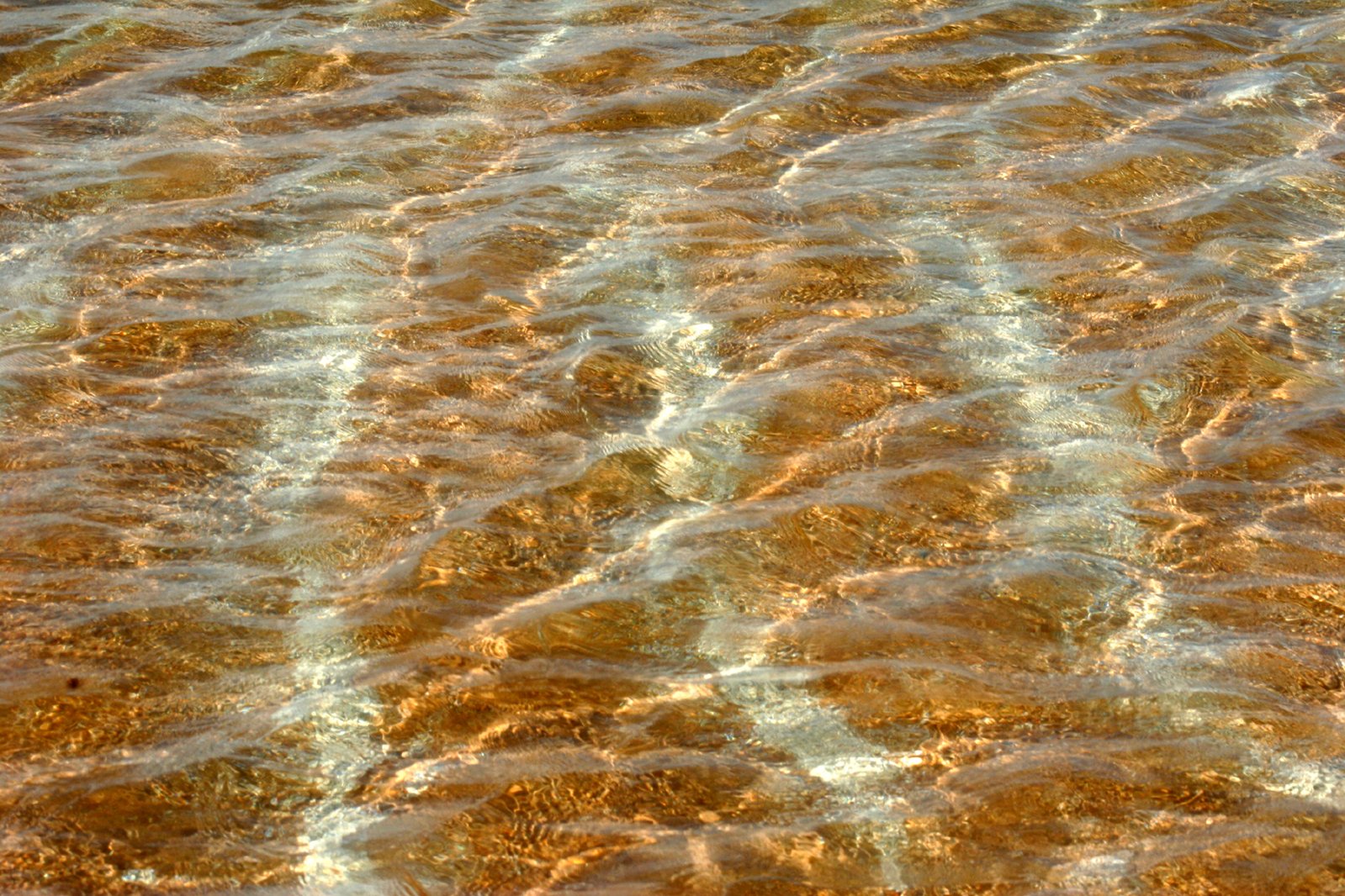 water in the ocean with gold colored ripples