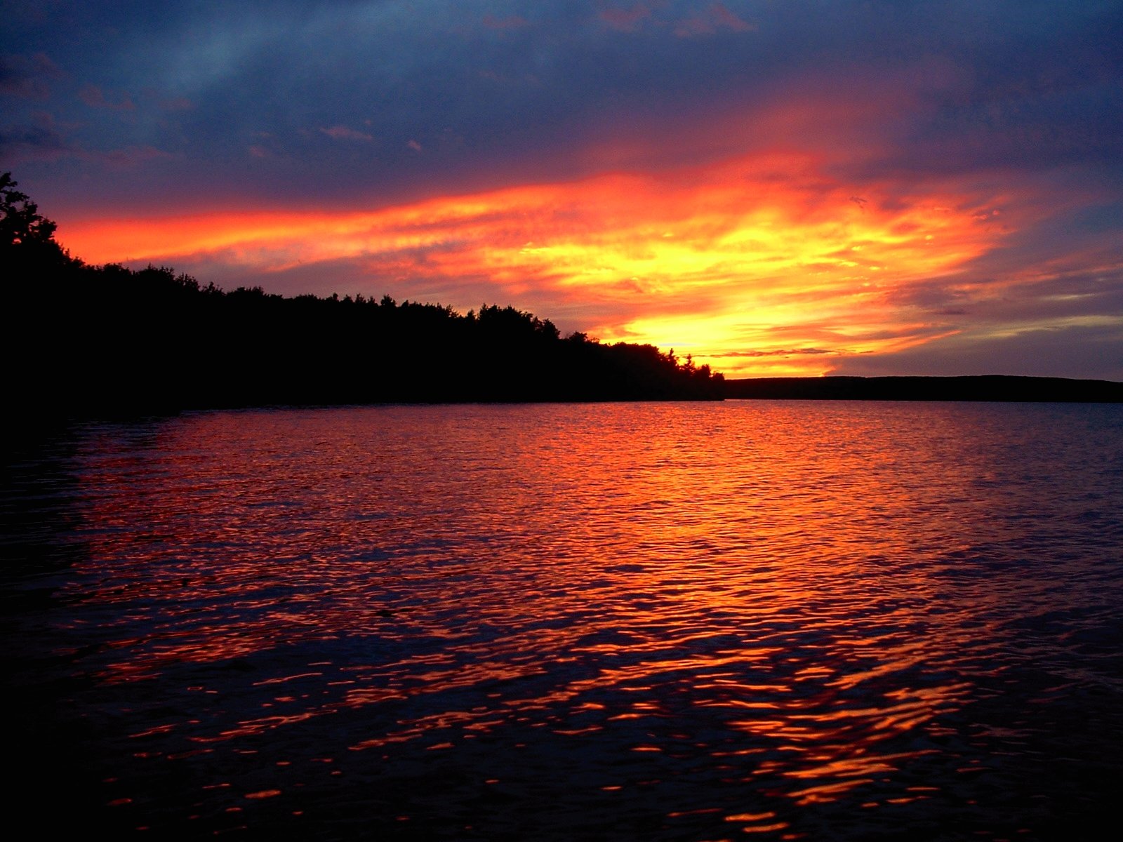 the sun setting on a lake, near an island