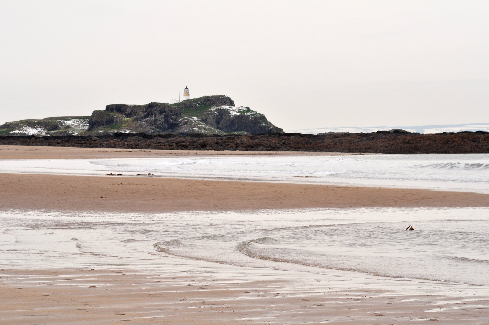 a sandy beach with water coming out from the ocean