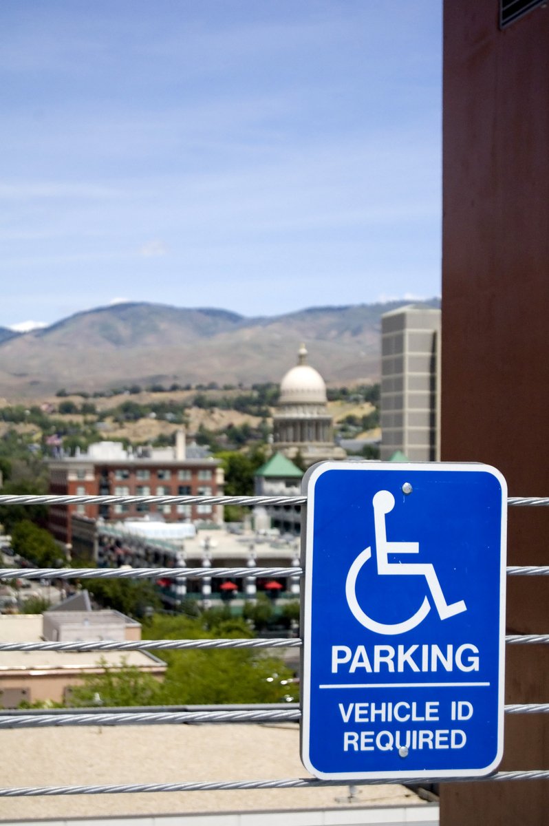 a blue handicapped parking sign near buildings in the background